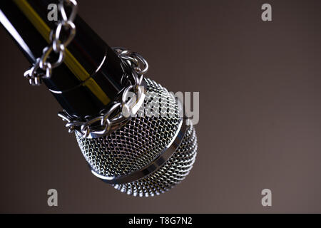 Microphone avec une chaîne, illustrant l'idée de la liberté de la presse ou la liberté d'expression sur fond sombre. Journée mondiale de la liberté de la presse concept. Banque D'Images