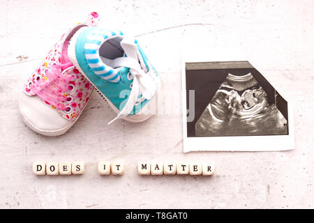 Chaussons pour bébé bleu et rose avec une photo de l'échographie pendant 20 semaines sur un fond clair. Est-il important d'inscription Banque D'Images