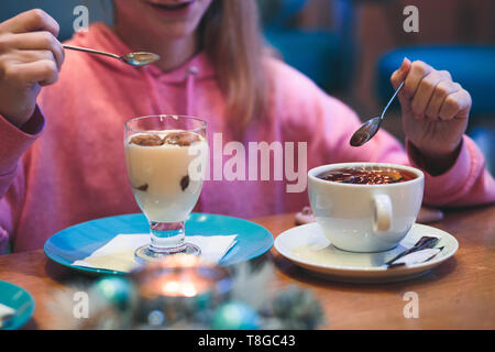 Fille de manger un dessert et de boire un thé dans un café. Les gens sincères, vrais moments, situations authentiques Banque D'Images