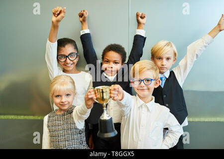 Les enfants multiculturels comme la création d'une entreprise avec une équipe d'encouragement de la coupe du gagnant Banque D'Images