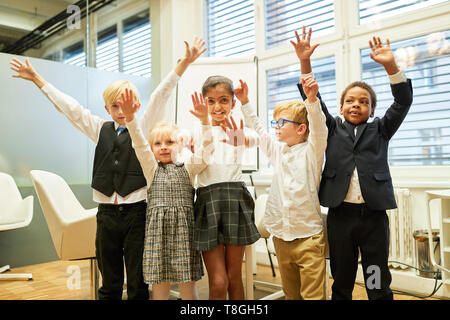 Groupe multiculturel d'enfants comme une entreprise réussie d'encouragement de l'équipe au bureau Banque D'Images