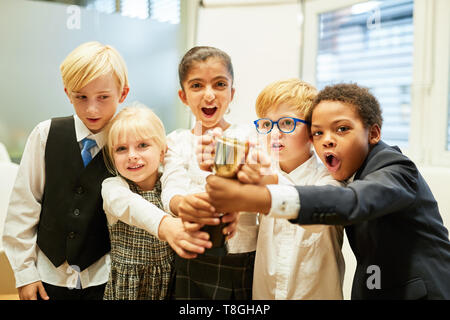 Les enfants d'encouragement réussi comme avec l'équipe d'entreprises multiculturelles trophée gagnant Banque D'Images