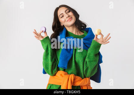 Portrait de femme joyeuse 30s dans des vêtements colorés holding macaron cookies tout en isolés sur fond blanc Banque D'Images