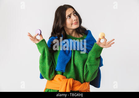 Portrait de femme joyeuse 30s dans des vêtements colorés holding macaron cookies tout en isolés sur fond blanc Banque D'Images