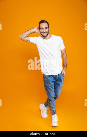 Longueur totale de l'image attractive man 30s avec barbe et moustache smiling while isolés sur fond jaune Banque D'Images