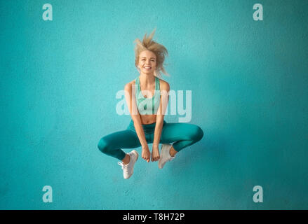 Sporty woman jumping près de mur de couleur Banque D'Images