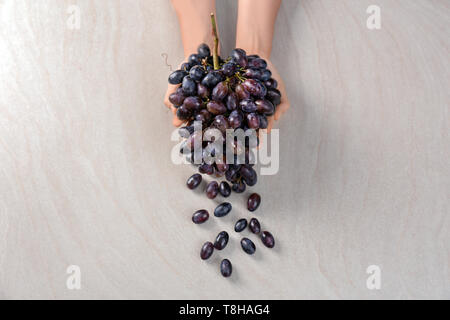 Femme tenant des raisins mûrs sur fond clair Banque D'Images