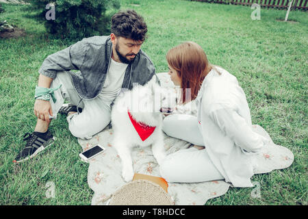 Transmission joyeuse beau couple d'amoureux assis sur l'herbe Banque D'Images