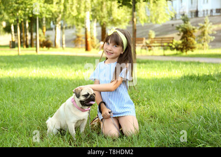 Cute little Girl with pug dog en journée d'été sur le parc Banque D'Images