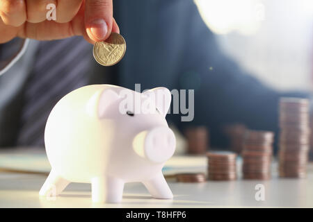 Côté businessman putting borne de l'argent dans pig Banque D'Images