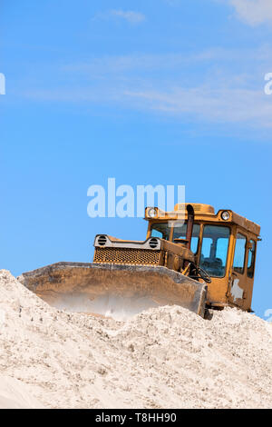 Bulldoser jaune sur le sable contre ciel bleu Banque D'Images