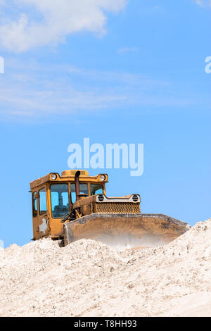 Bulldoser jaune sur le sable contre ciel bleu Banque D'Images