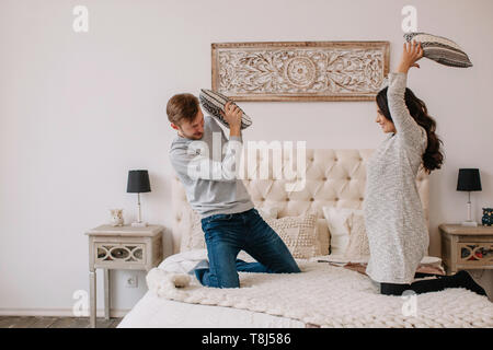 Couple having a pillow fight dans la chambre à coucher Banque D'Images