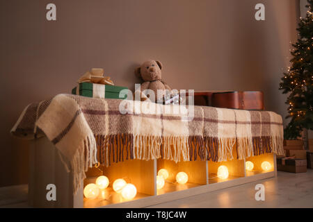 Étagère avec guirlande de noël lumineux et cadeaux dans la salle de séjour Banque D'Images