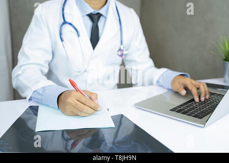Asian médecin travaille à l'ordinateur dans le bureau de la clinique - Image Banque D'Images