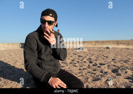 Guy fumer un cigare sur la plage. Banque D'Images