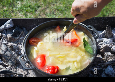 Cuisson processus shurpa soupe dans un grand chaudron en fonte à l'extérieur. L'alimentation d'été pour la randonnée. Une cuisine turque. Banque D'Images