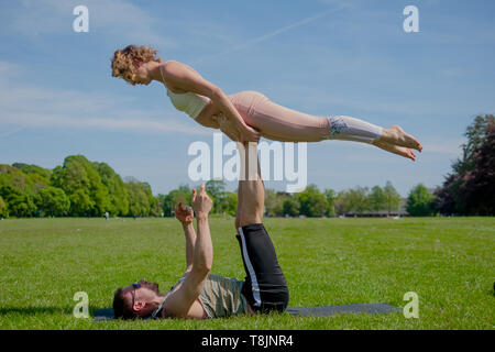 Les jeunes athletic couple in love performing yoga acro dans Roath Park par une belle journée ensoleillée. Banque D'Images