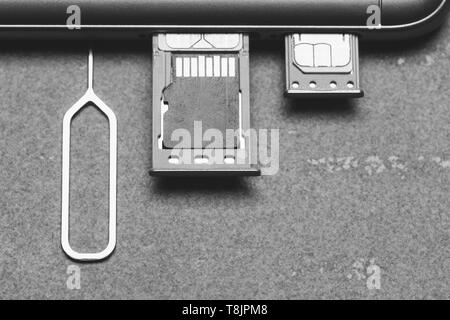 Smartphone avec emplacements SIM ouvert et micro carte mémoire SD sur un fond gris avec copie espace, top view close-up la photographie noir et blanc Banque D'Images