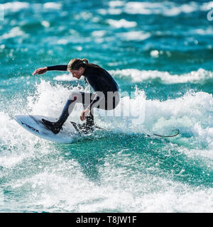 Action de surf comme une jeune adolescente manèges surfer une vague à Newquay dans Fistral à Cornwall. Banque D'Images