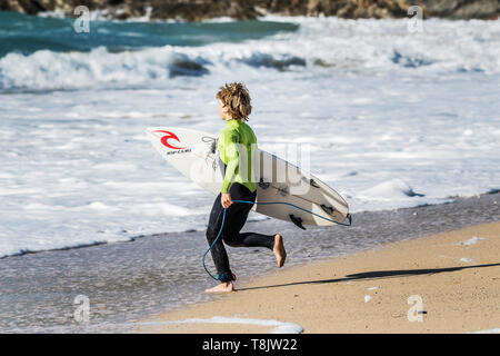 Un jeune internaute tournant dans la mer à la plage de Fistral à Newquay en Cornouailles. Banque D'Images