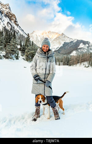 Jeune fille sur une marche avec son chien beagle en hiver s'amuser sur la neige première fois. Banque D'Images