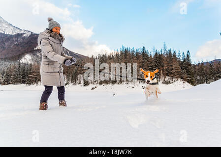 Jeune fille sur une marche avec son chien beagle en hiver s'amuser sur la neige première fois. Banque D'Images