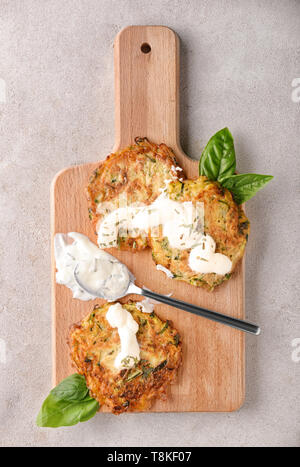 Crêpes de courgettes avec de la sauce sur planche de bois Banque D'Images