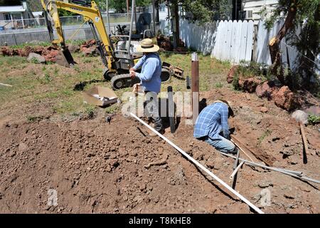 Déménagement roches et installation de la tuyauterie pour l'aménagement paysager, par travailleurs mexicains à l'aide de pelleteuses et des outils à main pour le chargement et de compensation des lots dans le comté de Lake CA Banque D'Images