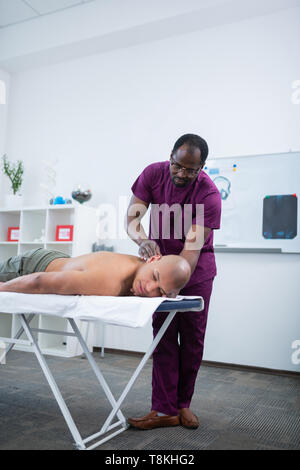 Dark-skinned massothérapeute le massage corps de sportif Banque D'Images