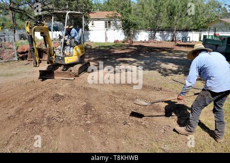 Déménagement roches et installation de la tuyauterie pour l'aménagement paysager, par travailleurs mexicains à l'aide de pelleteuses et des outils à main pour le chargement et de compensation des lots dans le comté de Lake CA Banque D'Images