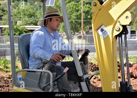 Déménagement roches et installation de la tuyauterie pour l'aménagement paysager, par travailleurs mexicains à l'aide de pelleteuses et des outils à main pour le chargement et de compensation des lots dans le comté de Lake CA Banque D'Images