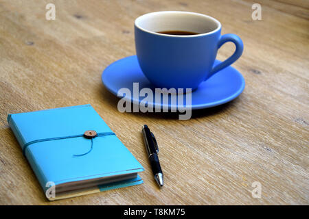 Tasse de café, ordinateur portable bleu et un stylo sur une table en bois Banque D'Images