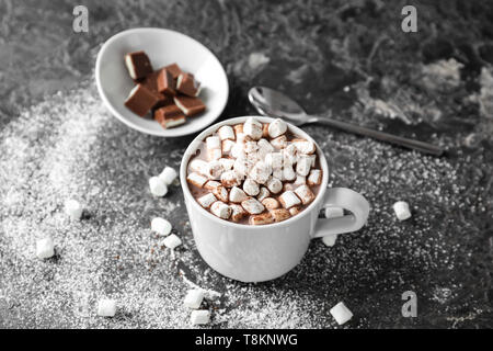 Tasse de cacao délicieux avec des guimauves et du chocolat sur table grunge Banque D'Images