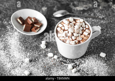 Tasse de cacao délicieux avec des guimauves et du chocolat sur table grunge Banque D'Images