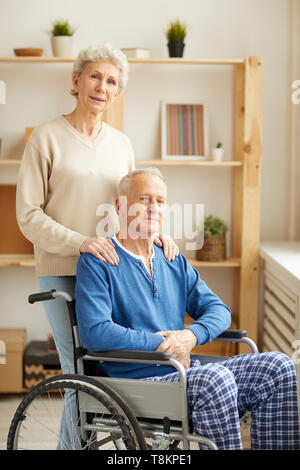 Femme posant avec un mari en fauteuil roulant Banque D'Images