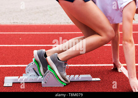 Une école pratique des femmes venant des blocs en athlétisme et pratique sur une piste rouge. Banque D'Images