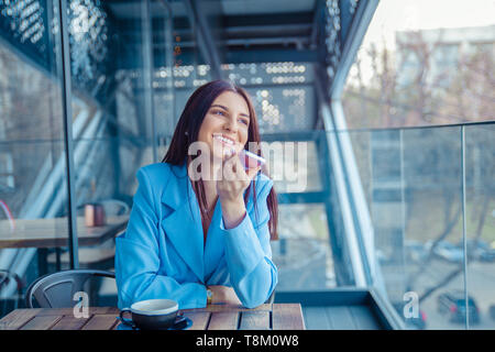 Portrait d'une fille à l'aide de la reconnaissance vocale du téléphone assis dans un café cosy branché cafe à Manhattan New York. Closeup portrait of a bea Banque D'Images