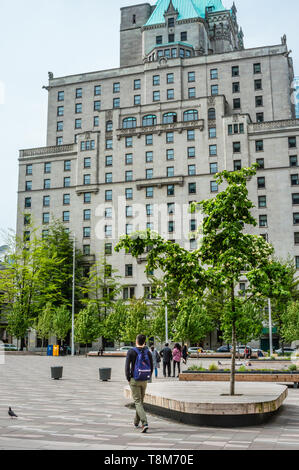 Sac à dos porte piéton mâle de marcher à travers Vancouver Art Gallery North Plaza Hotel Vancouver avec façade est en arrière-plan. Banque D'Images