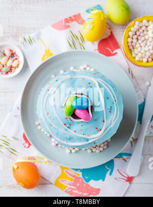 Gâteau de Pâques avec des œufs colorés. Fond en bois blanc. Vue d'en haut. Banque D'Images