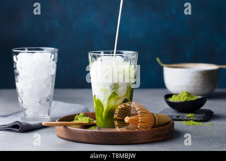 Thé Vert Matcha, thé glace affluent dans le grand verre sur plaque de bois. Arrière-plan de pierre grise. Banque D'Images