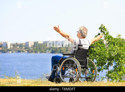 Happy senior man in wheelchair near river Banque D'Images