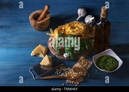 Faire de pesto. Le tableau avec le Pesto au basilic ingrédients pour produire. Mortier, herbes basilic frais, noix de pin, l'huile d'olive, le parmesan, l'ail, bol avec p Banque D'Images