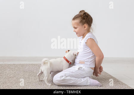 Animal de compagnie, les enfants et animaux - concept enfant fille assise sur le sol et l'alimentation chiot Banque D'Images