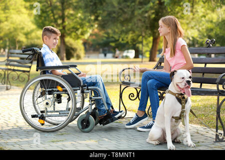 Garçon handicapé avec sa sœur et le chien se reposant dans park Banque D'Images