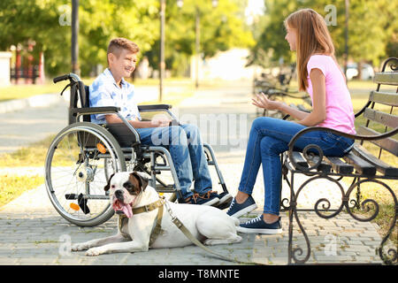 Garçon handicapé avec sa sœur et le chien se reposant dans park Banque D'Images