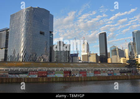 Bâtiment industriel, avec des murs couverts de graffitis sur la rive nord du fleuve Yarra moderne avec des immeubles de grande hauteur en arrière-plan. Banque D'Images