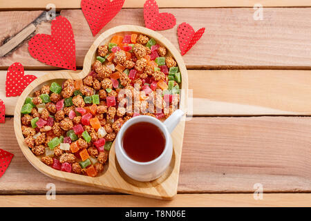 Fruits secs colorés dans un plateau en forme de coeur avec plateau Banque D'Images
