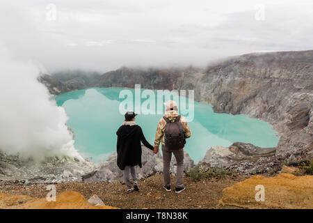 Couple de touristes regarde le lac du soufre sur le volcan Ijen sur l'île de Java en Indonésie. Les randonneurs billet sur top mountain, travel concept Banque D'Images