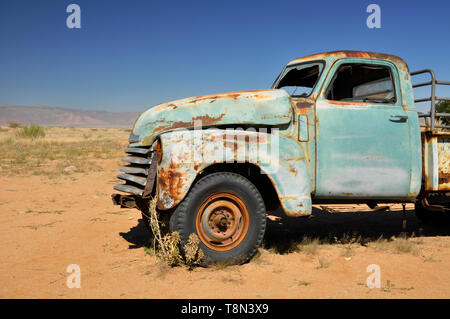 Épave de voiture ancienne rouillée abandonnée dans la colonie isolée de Solitaire, en Namibie, entourée par le paysage désertique africain Banque D'Images